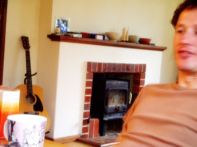 a man sitting in front of a fireplace with a guitar