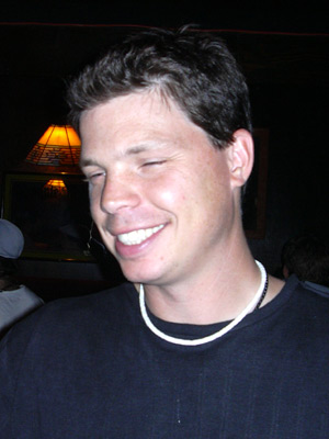 a smiling guy is wearing a necklace around his neck