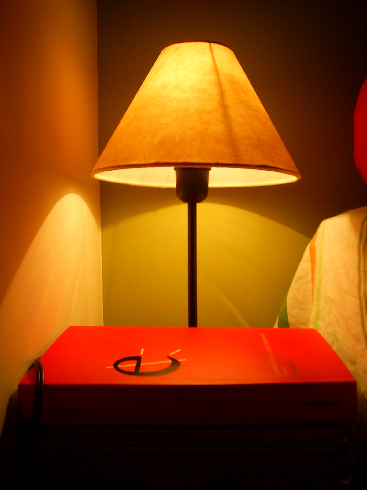 the lamp is lit over the red book on the nightstand