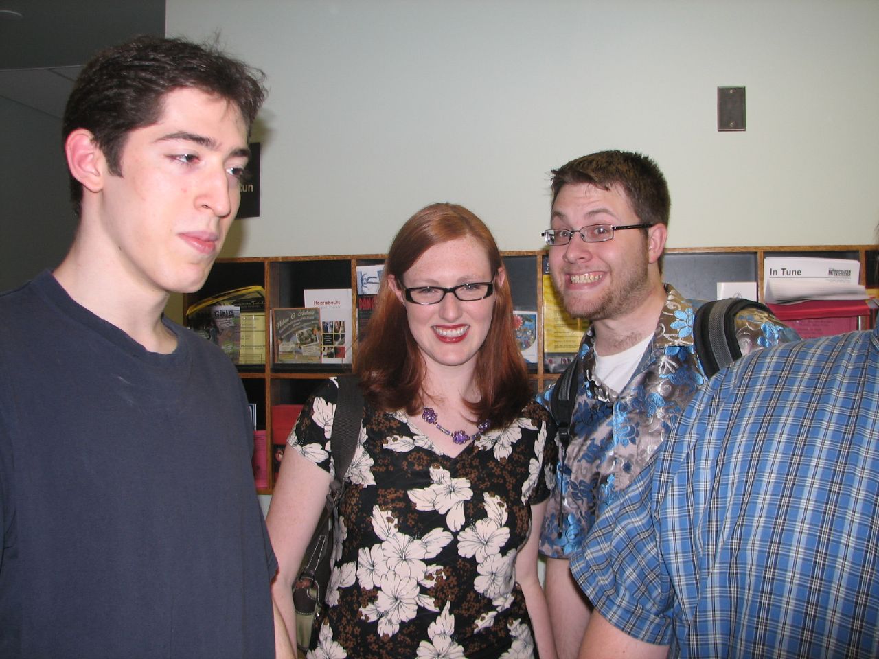 three people standing next to each other near a bookshelf