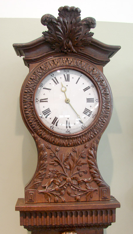 an old - fashioned clock stands on a shelf with a carved frame
