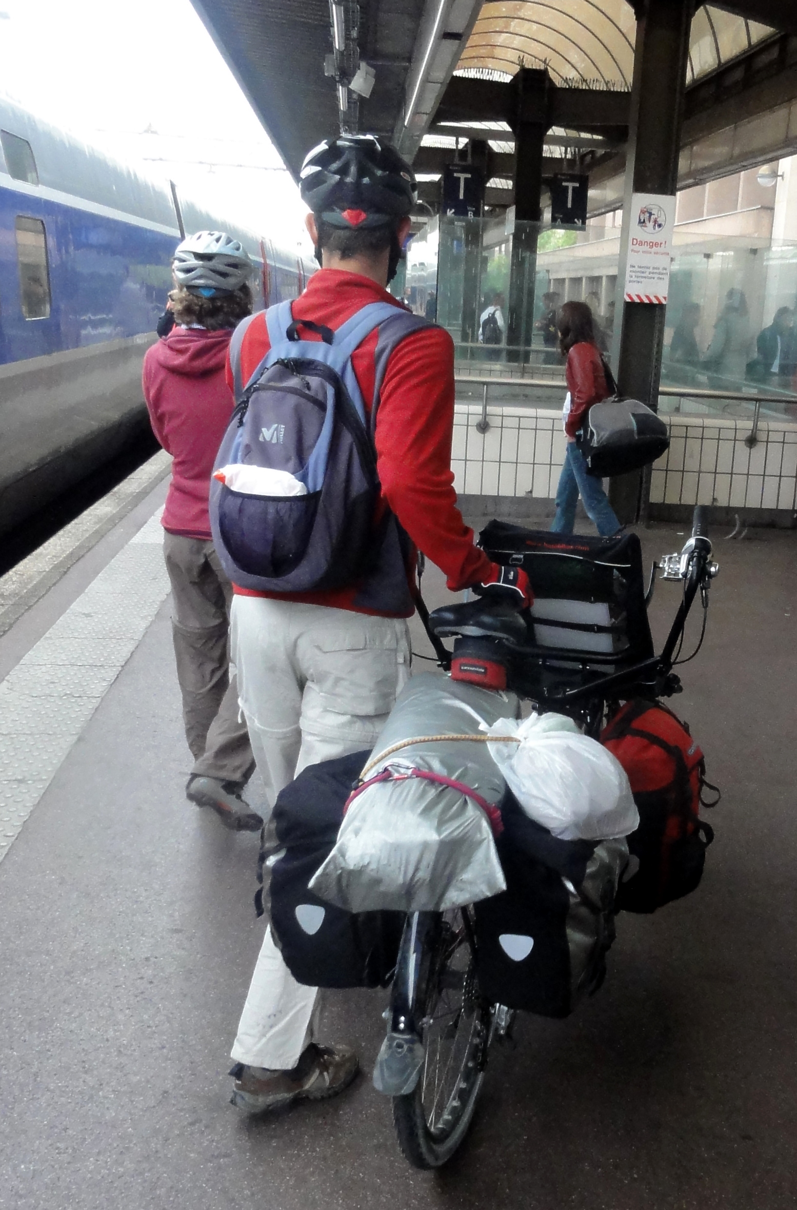 three people are waiting for the train at the station