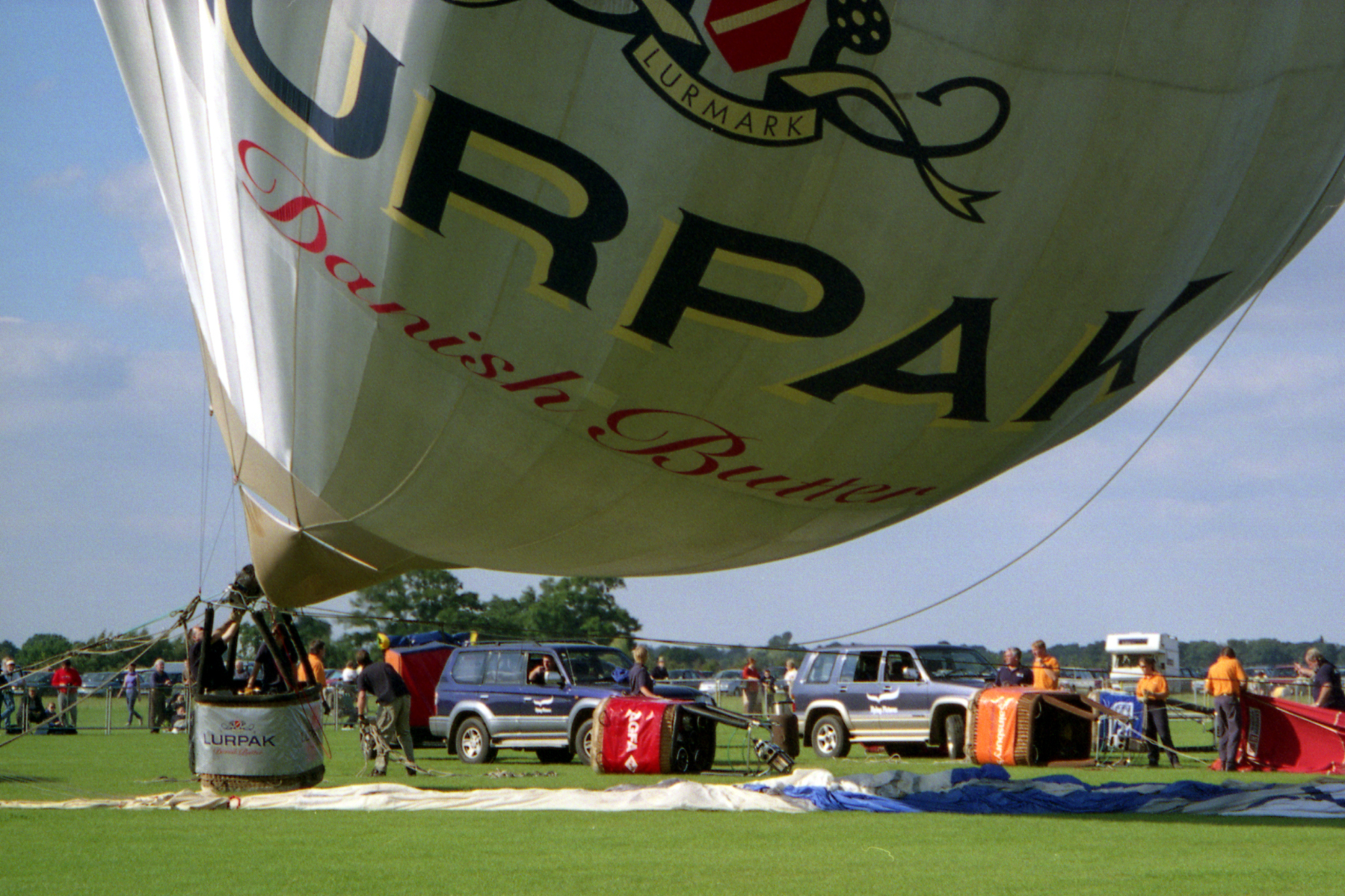 some people and trucks are next to the large inflated balloon