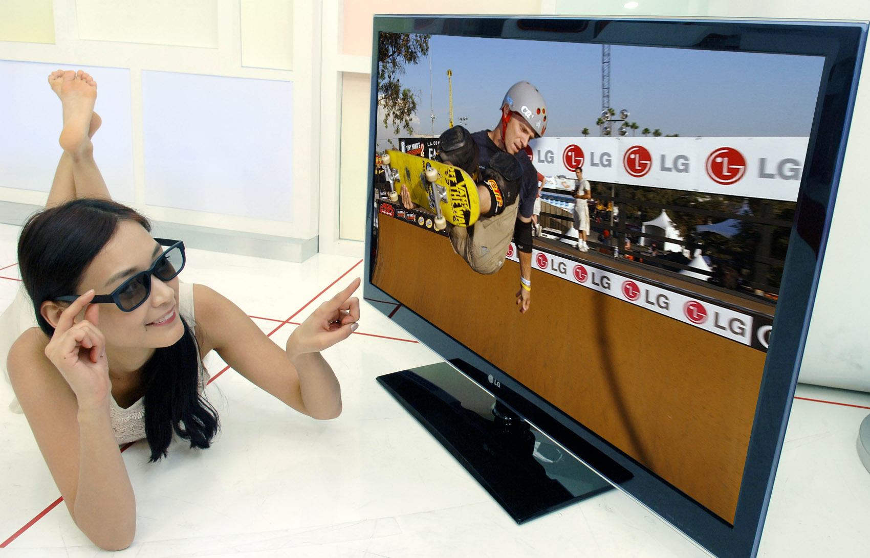 woman smiling in front of flat screen television with man on it