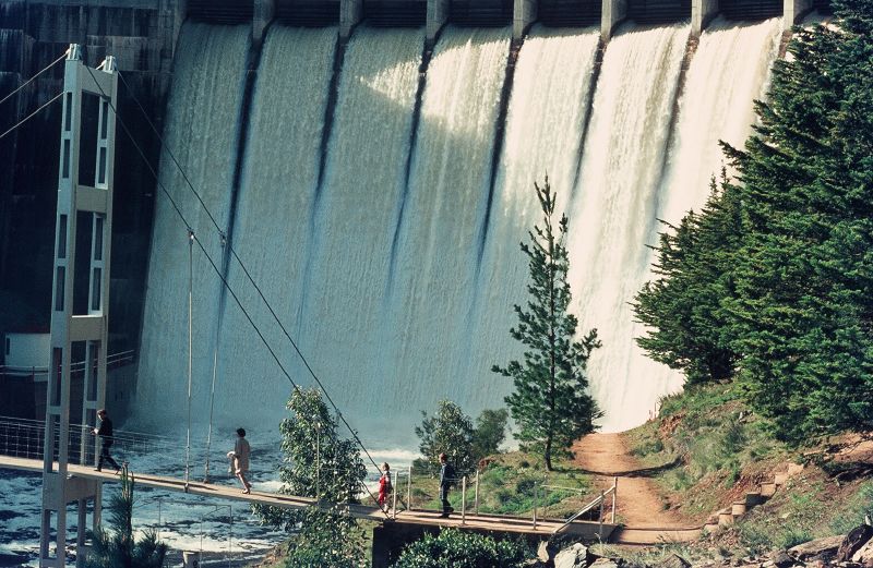 people on a rope walk next to a huge dam
