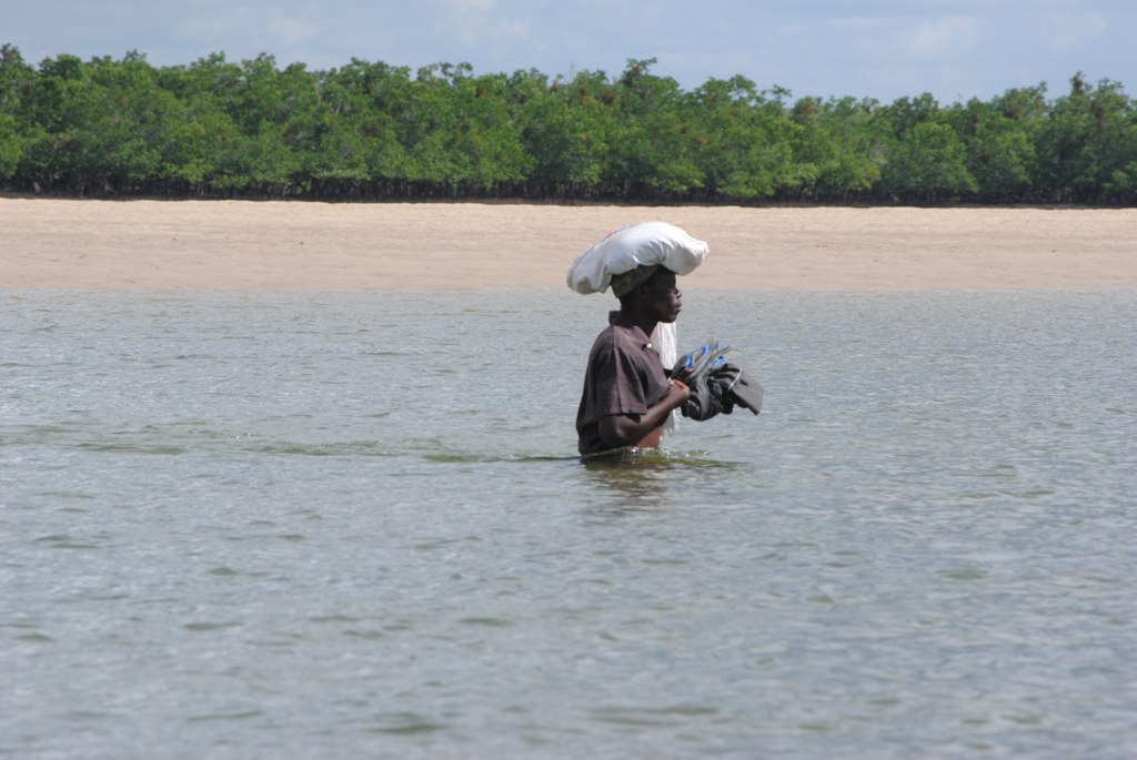a man wades through the water with a large bag on his head
