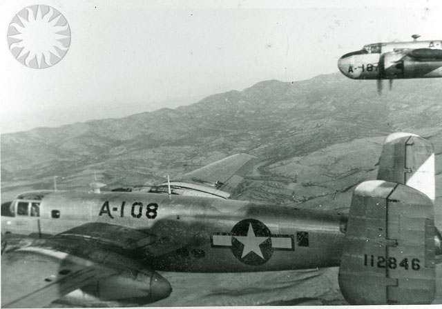 two airplanes fly close to each other near mountains