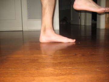 a pair of feet are standing on a wood floor