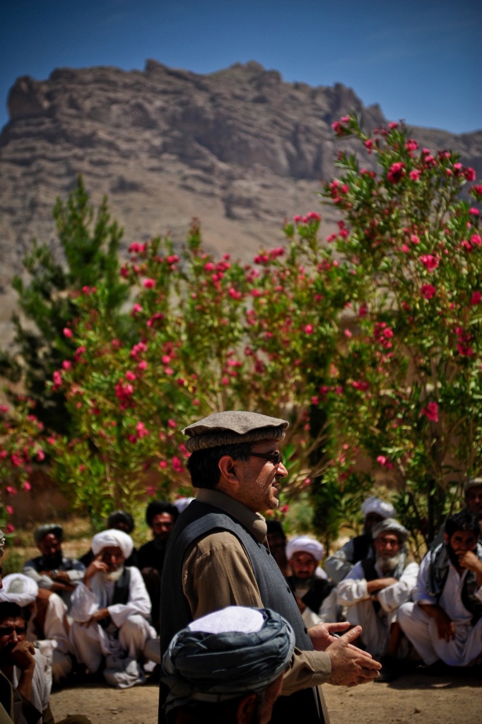 a man wearing a brown hat standing in front of some flowers