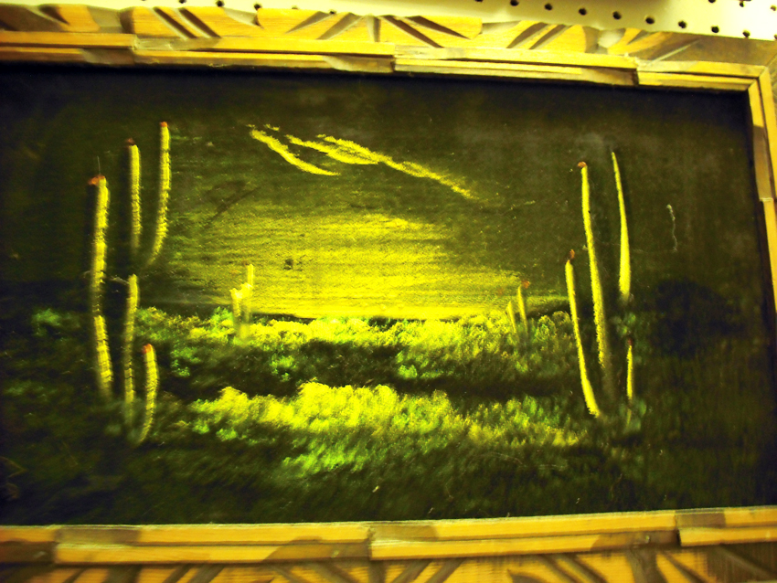 the painting shows a green, yellow and black field with cactus in it