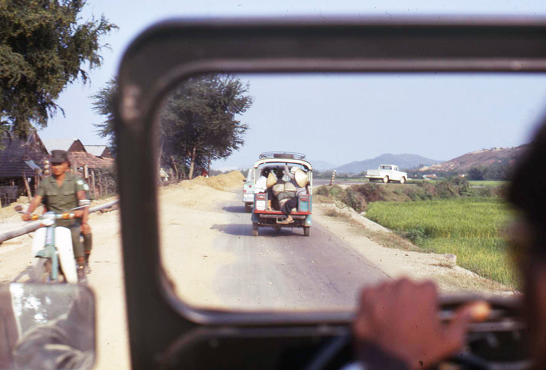 the man rides in a cart with three animals while the other one is driving down a road
