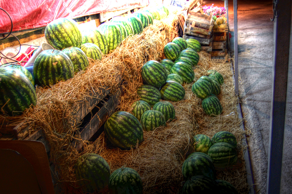 large watermelons and hay piled on bales in a shop