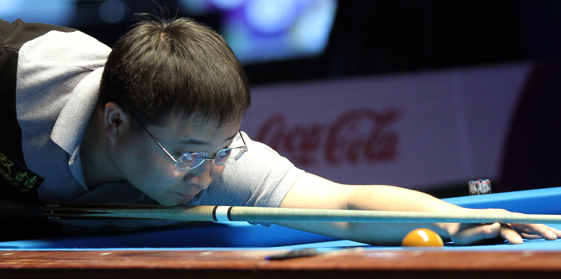 man in glasses playing pool on a blue table