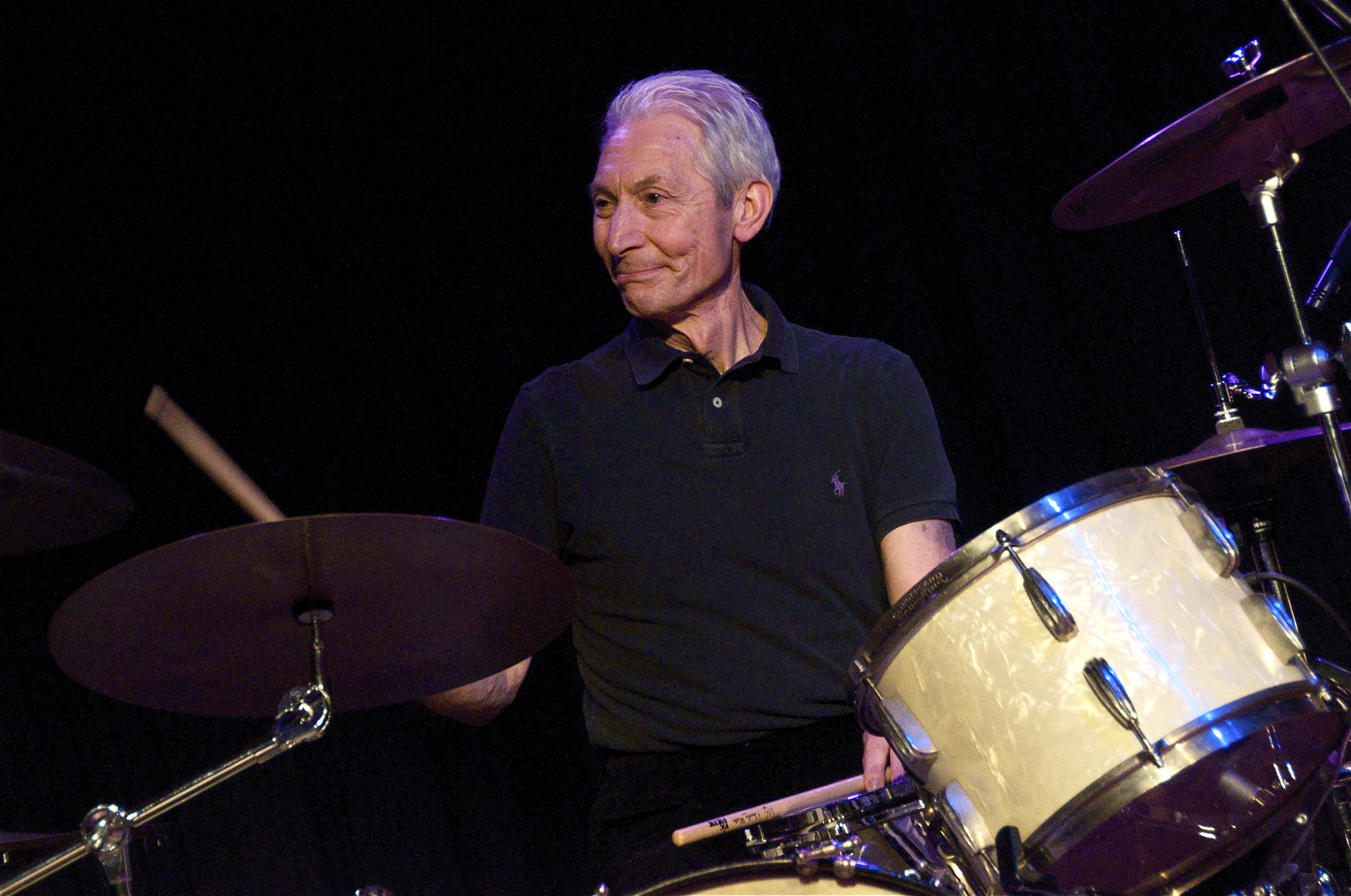 a man with gray hair is playing drums