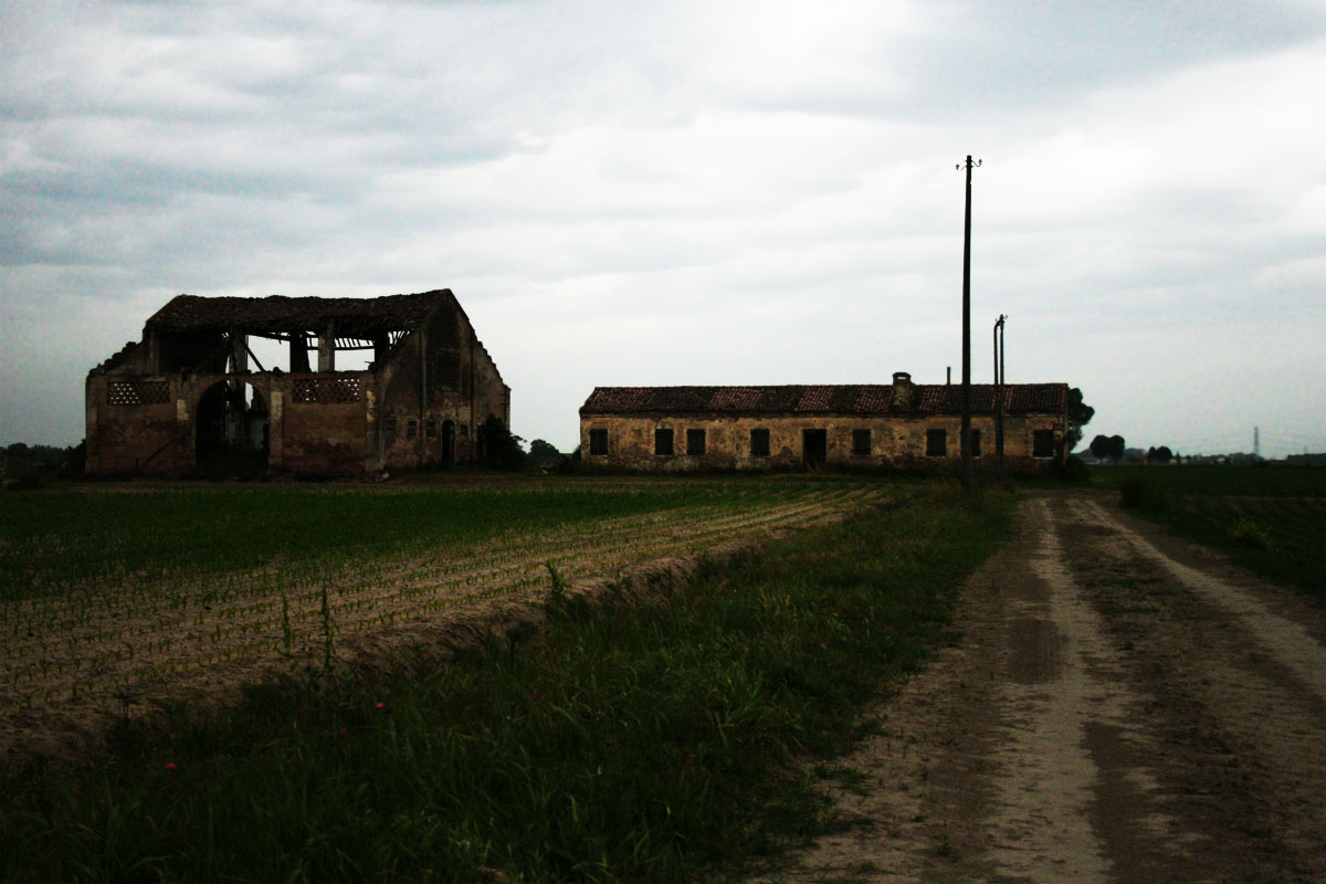 an old rundown building stands near a dirt road