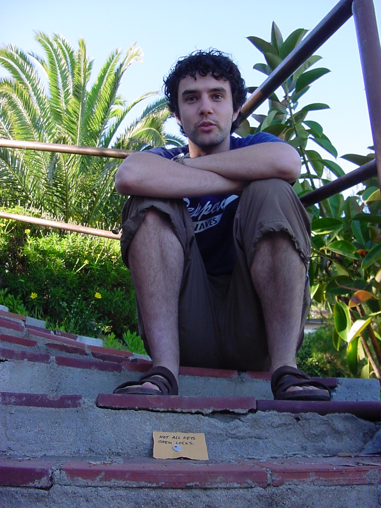 a young man sitting down and thinking while holding a stick