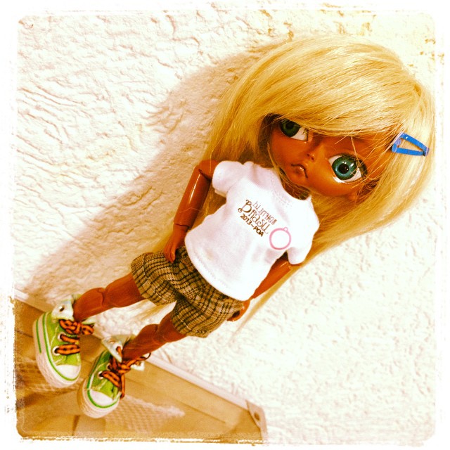 a doll with huge glasses wearing a shirt and plaid shorts