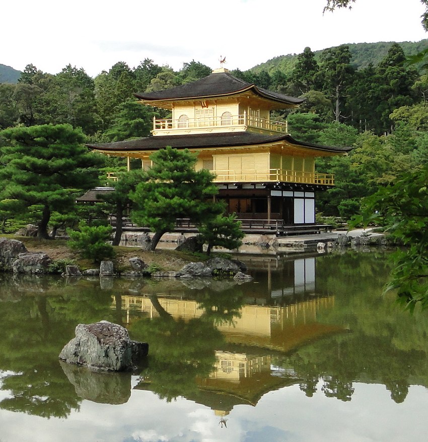 a golden pavilion and lake surrounded by green trees