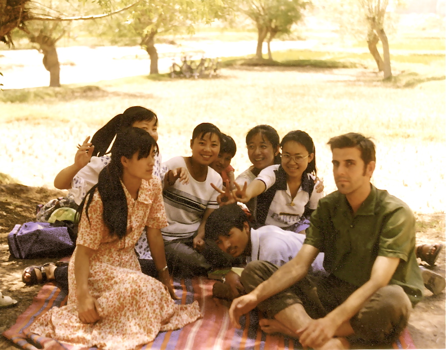 a group of people gathered on a blanket under some trees