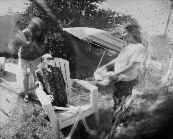 two people stand in the grass with a chair in front of them