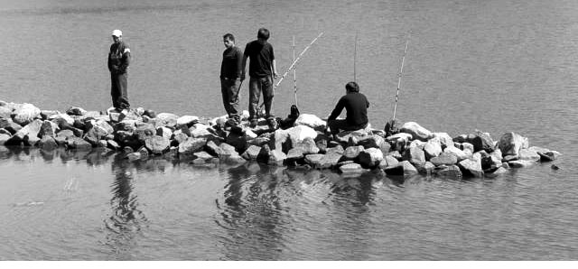 two men sitting on a rock break in the water