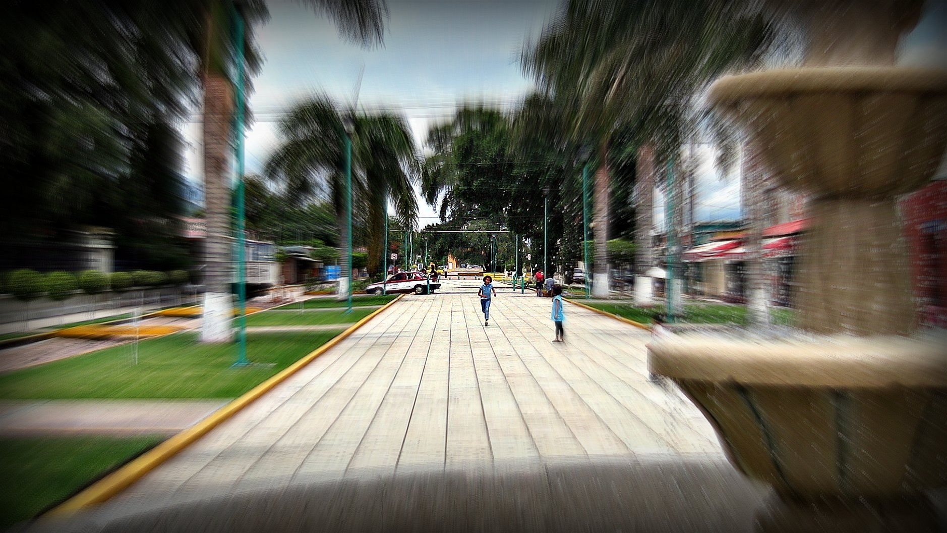 two children are walking in the street beside a fountain