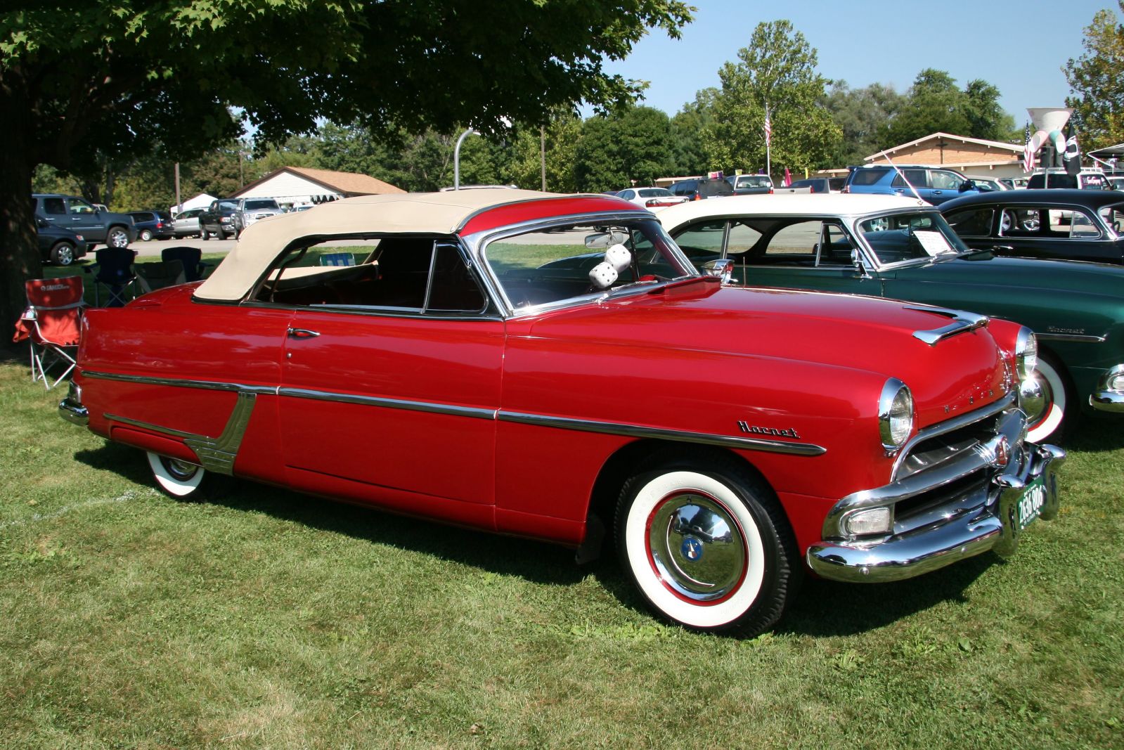 a very old red car with white wheels at an auto show