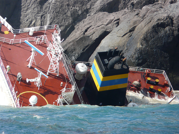 a big boat with an orange and yellow top is stuck to shore