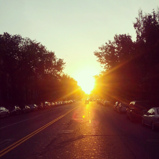 the sun shines brightly down on a street with cars