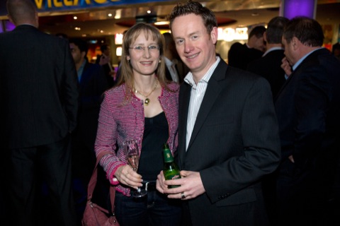 two people standing together at an event with some food and drink