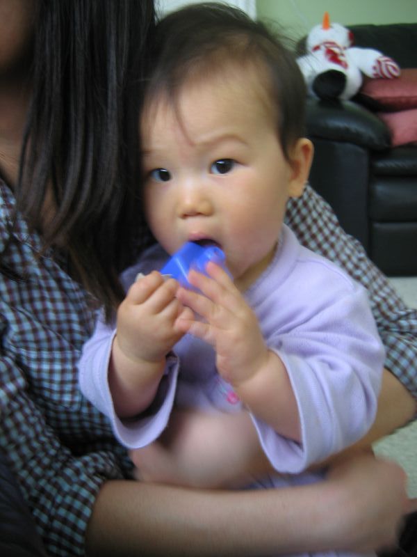 a woman is holding a baby and chewing on a toothbrush