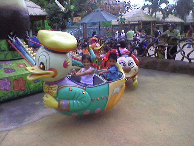 a little girl riding in an alligator toy ride