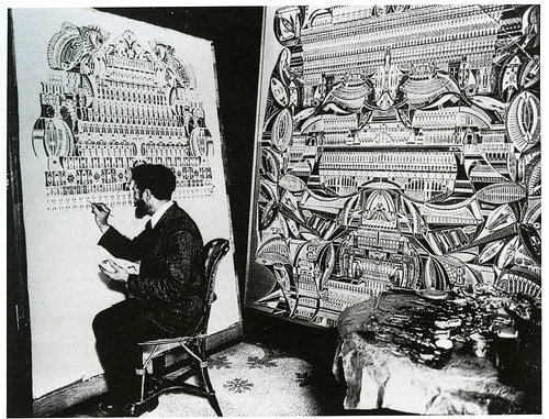 a woman sitting next to an artwork and writing on the easel