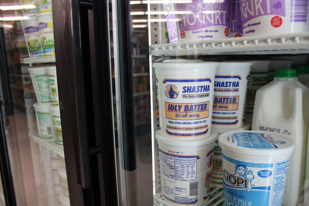 milk and yogurt sitting on shelves inside a refrigerator