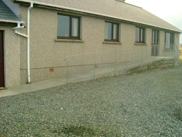 small building with garage and gate in gravel field