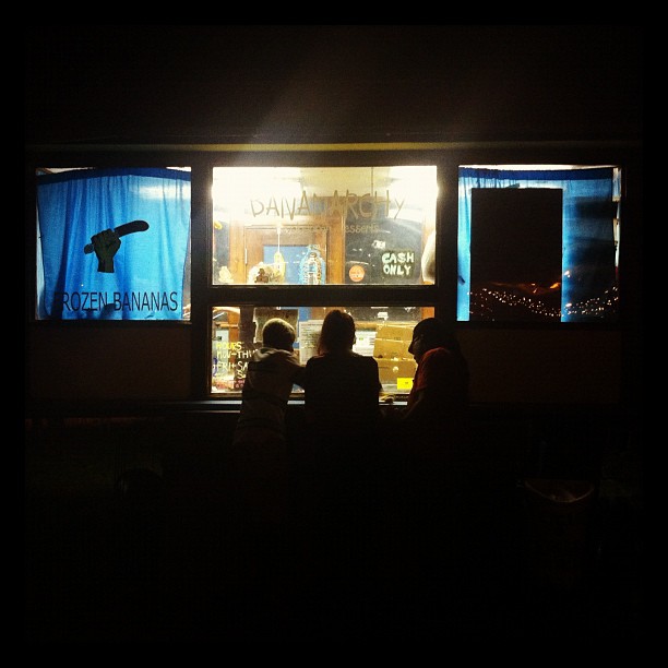 three people sitting in front of a store window at night