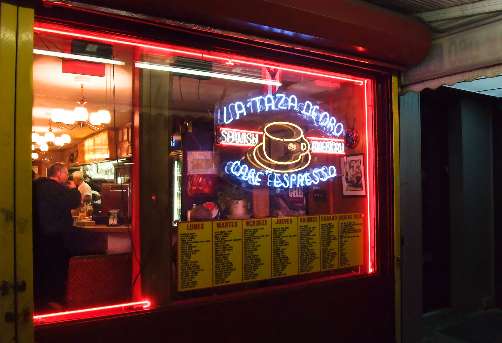 the window of a diner with neon signs outside