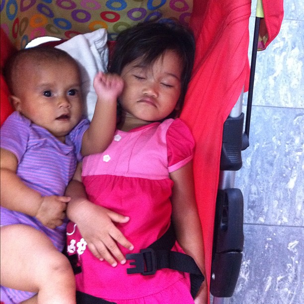 two small children are laying next to each other in a stroller