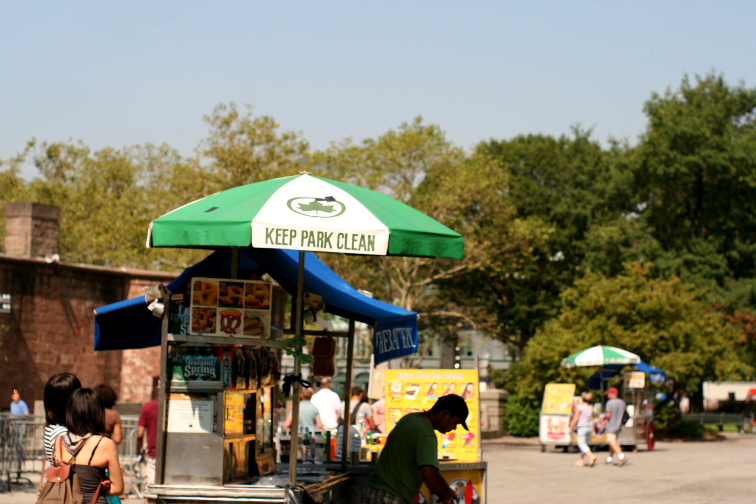 a man standing outside in front of a stand with a green umbrella over it
