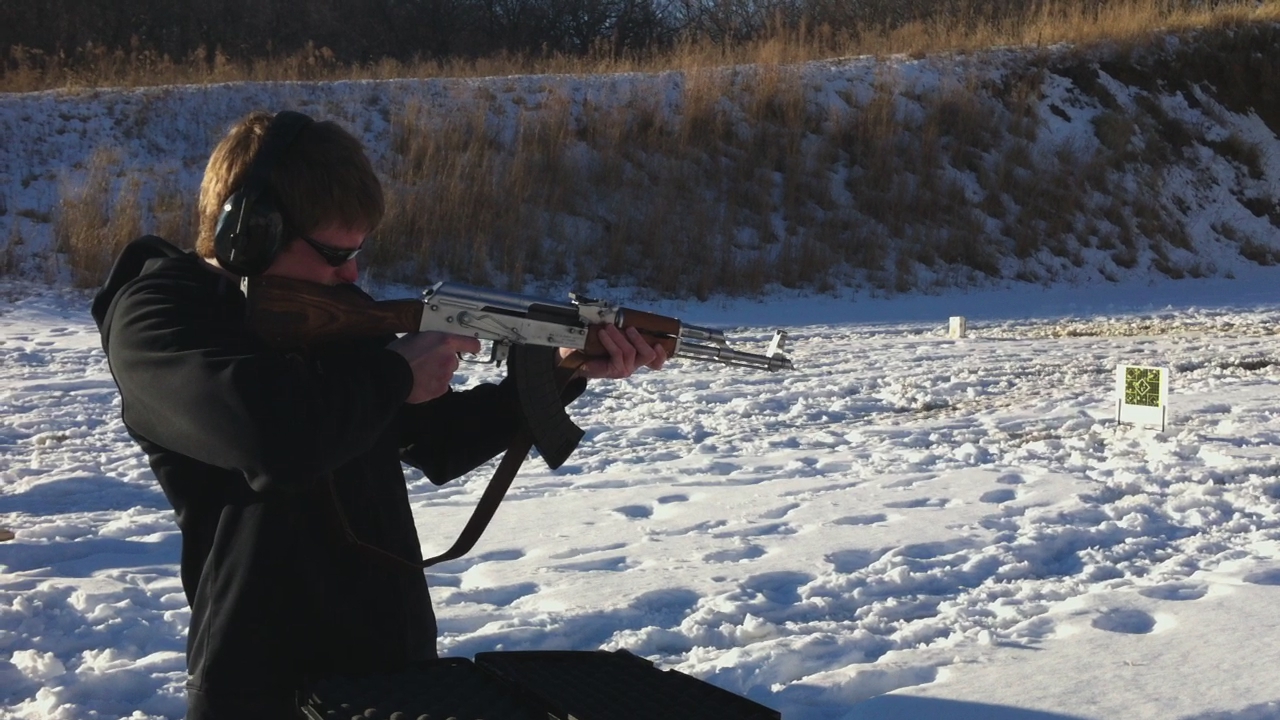 a woman with glasses is shooting at a rifle in the snow