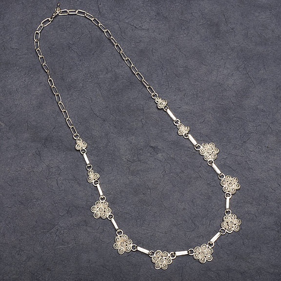 a necklace with intricate details on a black surface