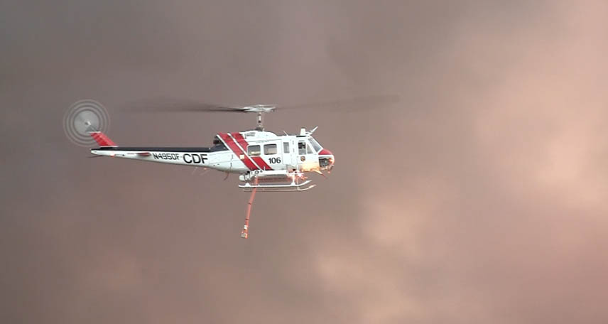 a helicopter flying in a cloudy sky with two lights on