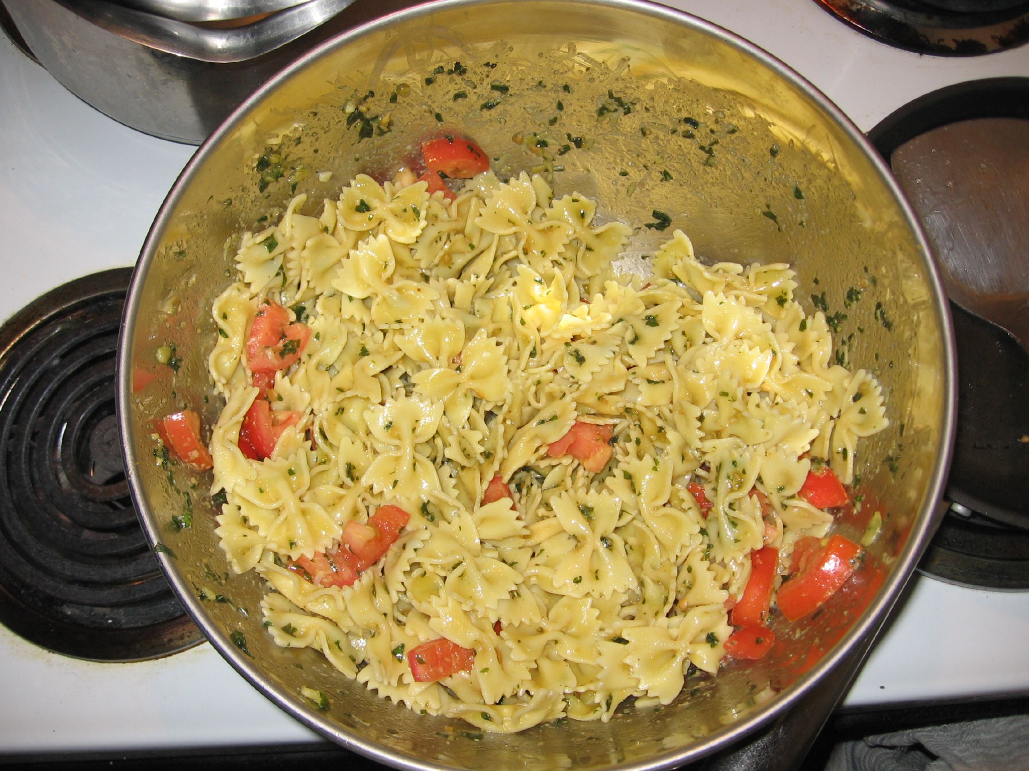 some pasta with tomato slices and cheese in a large metal bowl