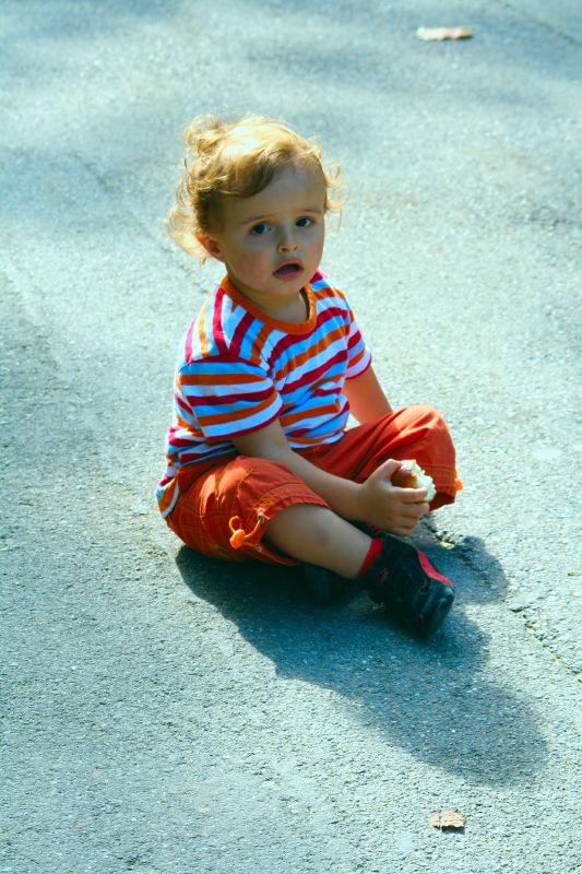 a small child sits on a street playing