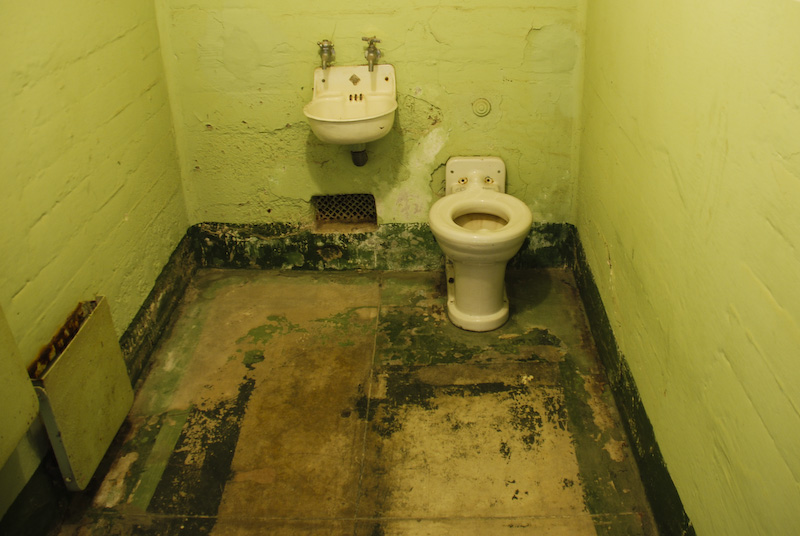 a green walled room with two old toilets