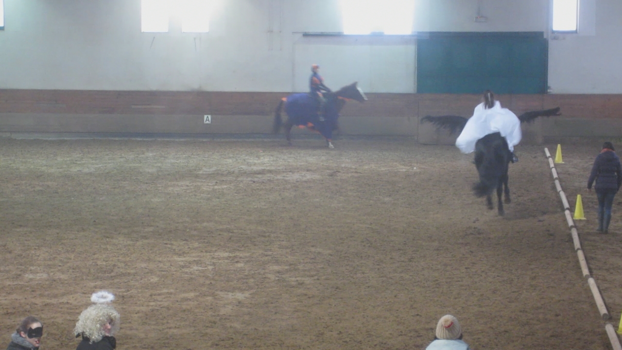 two women riding horses through an arena on either side of a fence