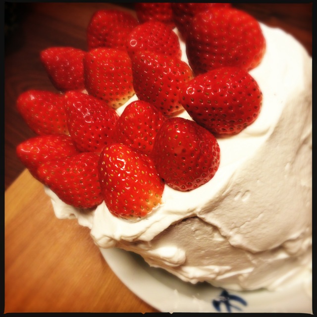a white cake covered in strawberries is shown