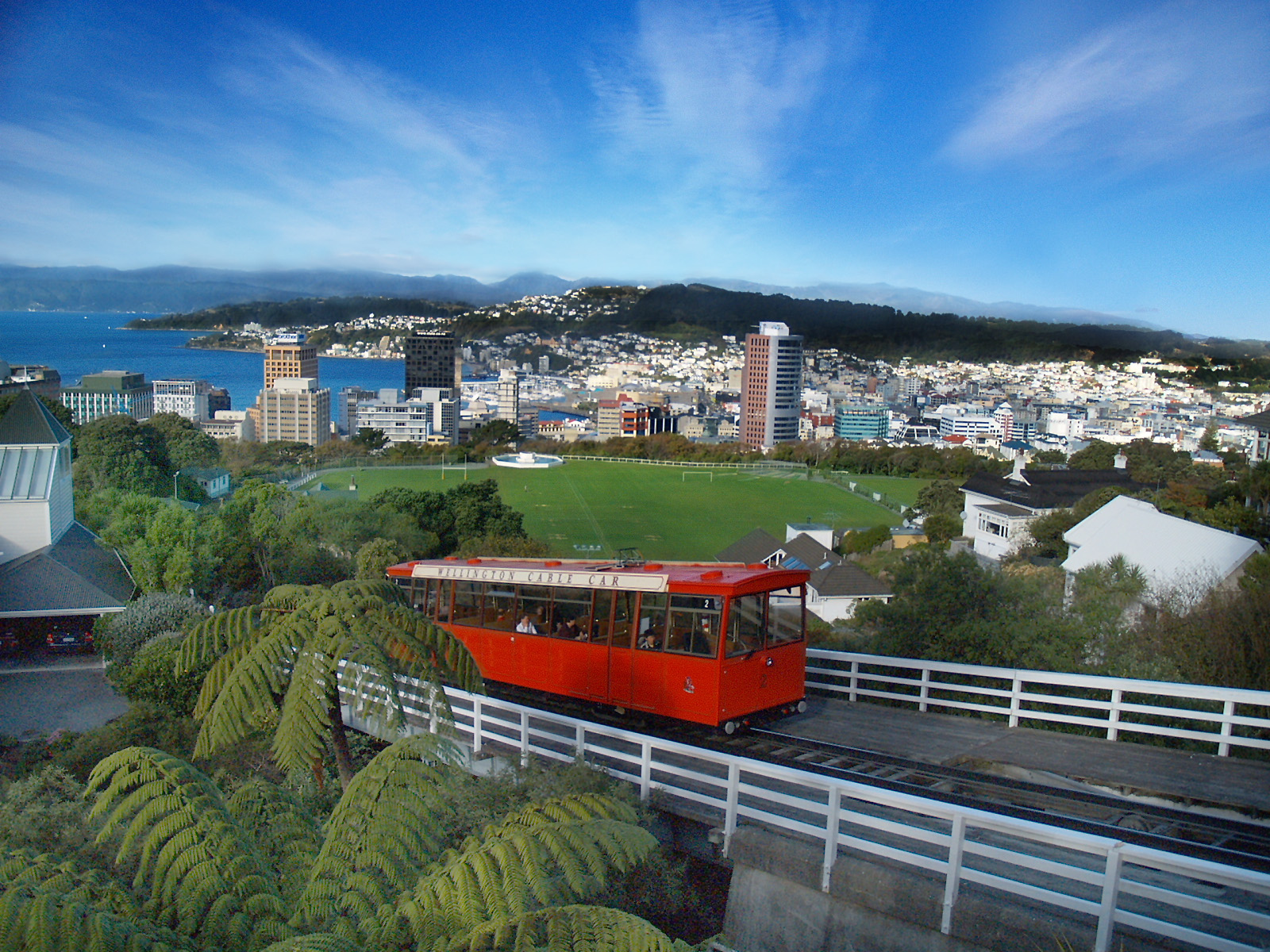 a red train riding on top of tracks next to a large city