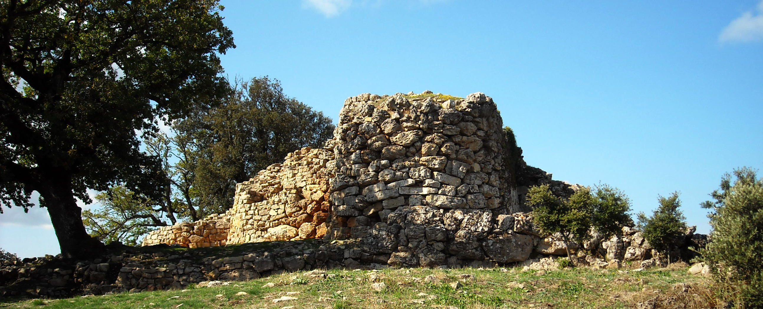 a stone structure on a hill with trees around it