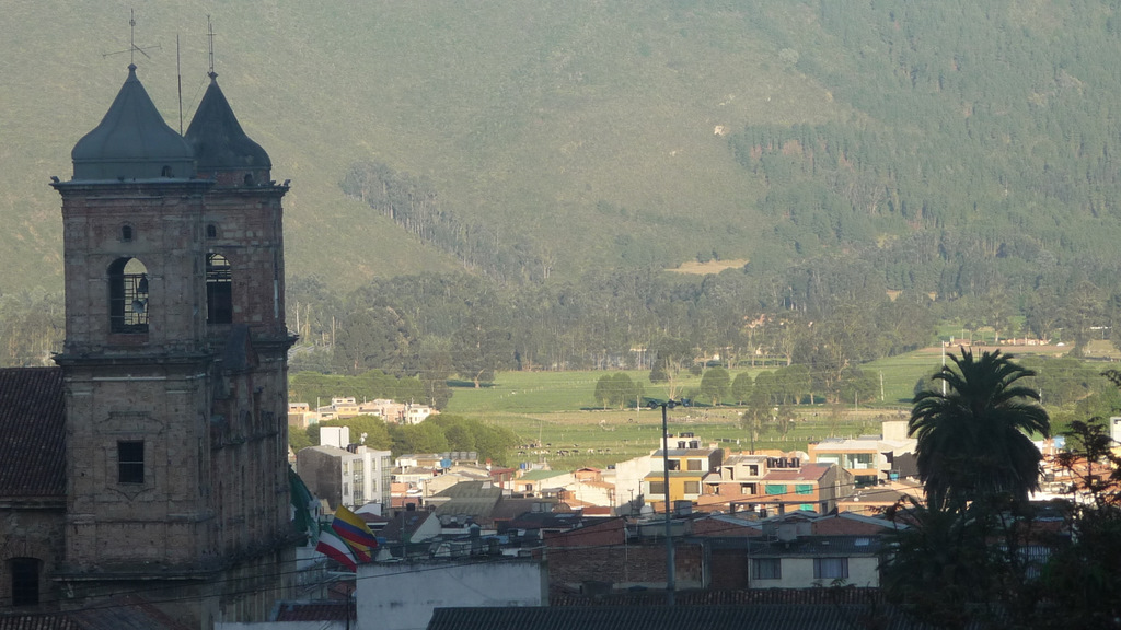 a tower with a clock near some mountains